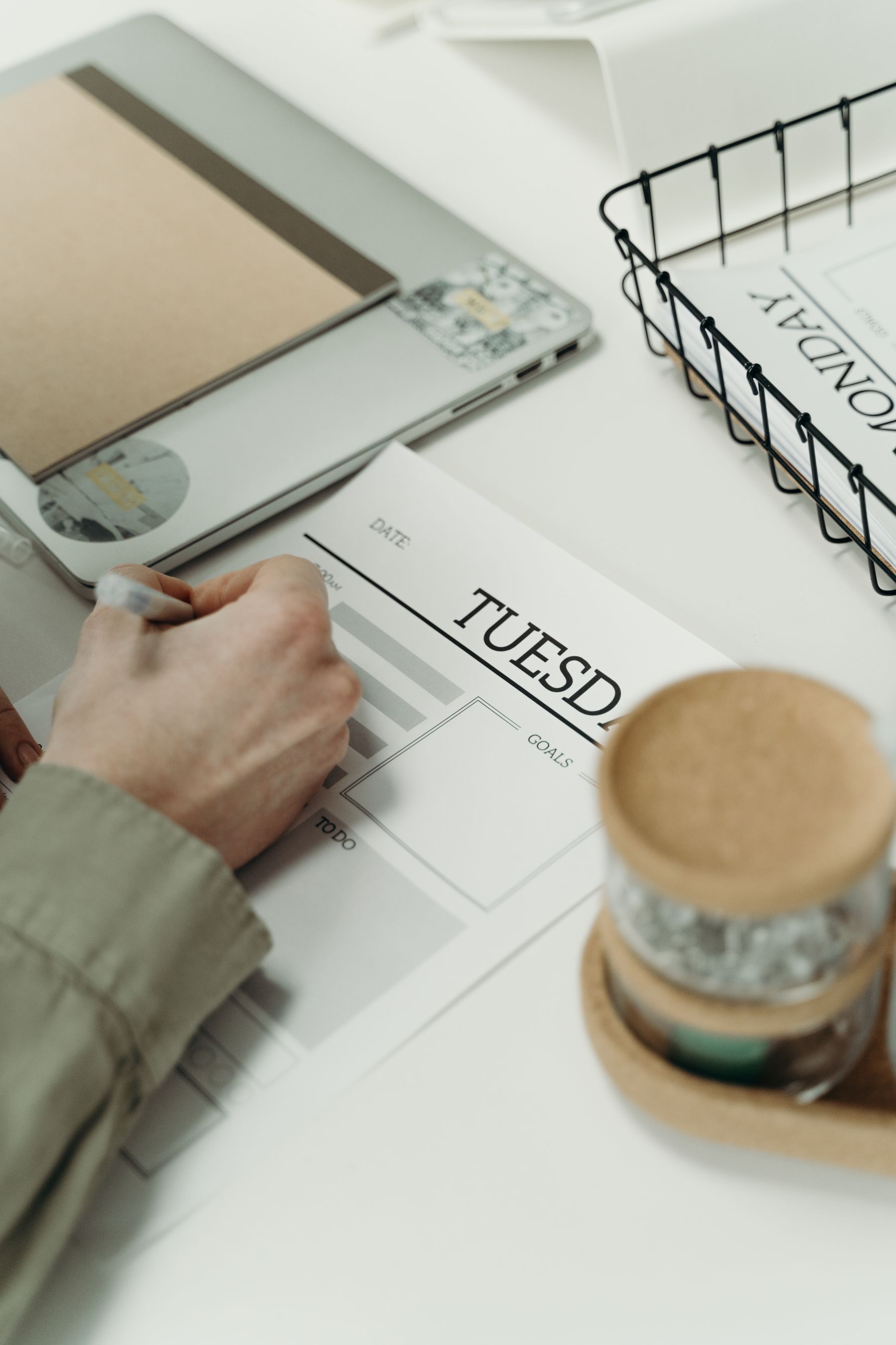 Close-up of a person writing goals in a daily planner at a clean desk